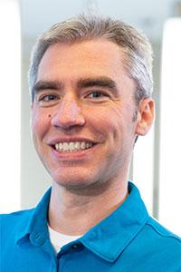 Man with grey hair wearing a blue collared shirt